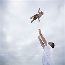 Father throwing young child in the air. Photo. FBP