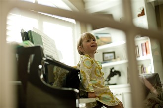 Young girl sitting on piano. Photo. Tim Pannell
