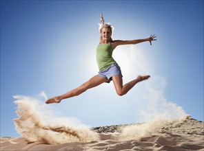 Female dancer jumping in sand. Photo : Mike Kemp
