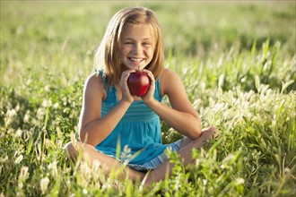 Young girl holding an apple. Photo : Mike Kemp
