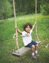 Young child sitting on large outdoor swing. Photo : Shawn O'Connor
