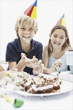 Children eating birthday cake with their hands. Photo. momentimages