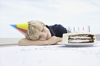 Young boy daydreaming about birthday cake. Photo : momentimages