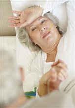 Senior woman with a thermometer in her mouth. Photo. momentimages