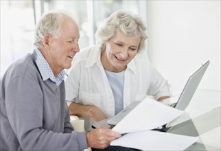 Senior couple doing paperwork together. Photo. momentimages