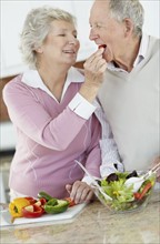 Senior couple preparing salad together. Photo. momentimages