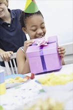 Young girl opening a birthday gift. Photo : momentimages
