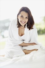 Smiling brunette woman wearing a bathrobe. Photo. momentimages