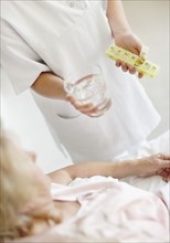 Nurse giving pill to senior woman. Photo. momentimages