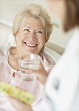 Nurse giving pill to senior woman. Photo. momentimages