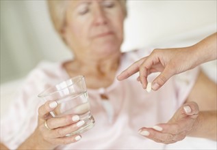 Nurse giving pill to senior woman. Photo : momentimages