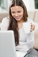 Woman drinking coffee while browsing the internet. Photo. momentimages