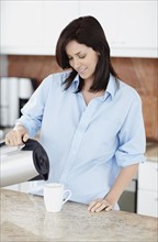 Brunette woman pouring coffee. Photo. momentimages