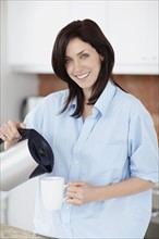 Brunette woman pouring coffee. Photo : momentimages