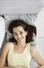 Cheerful brunette woman relaxing on couch. Photo : momentimages