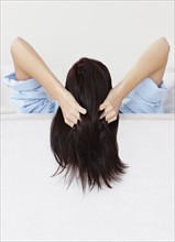 Brunette woman with her hands in her hair. Photo. momentimages