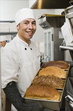 Chef holding tray of freshly baked bread.