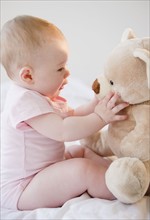 Baby playing with teddy bear. Photo. Jamie Grill