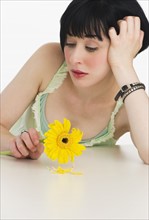 Sad woman holding a flower. Photo : Daniel Grill
