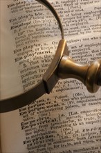 Magnifying glass over dictionary.