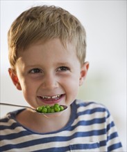 Young boy eating peas. Photo. Daniel Grill