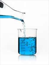 Blue liquid being poured into measuring cup. Photo. David Arky