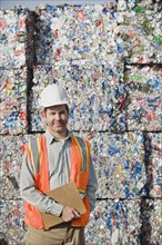 Worker standing in front of crushed aluminum cans. Photo. Erik Isakson