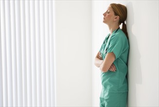 Tired doctor leaning against wall.