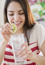 Woman squeezing lime into water. Photo. Jamie Grill