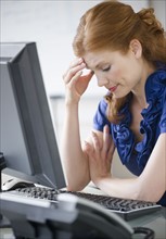 Frustrated businesswoman sitting at her desk. Photo. Jamie Grill