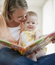 Mother reading book to her baby daughter. Photo. Jamie Grill