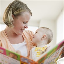 Mother reading book to her baby daughter. Photo : Jamie Grill