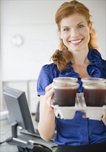 Businesswoman holding a tray of coffee. Photo. Jamie Grill