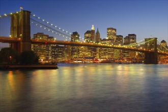Brooklyn Bridge and Jersey City buildings at night. Photo : Daniel Grill