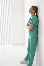 Tired healthcare worker leaning against wall.