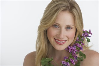 Blond woman holding purple flowers.