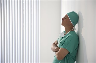 Tired healthcare worker leaning against wall.