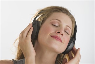 Blond woman listening to music with headphones.
