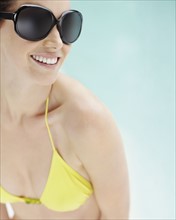 Brunette wearing bikini and sunglasses. Photo. momentimages