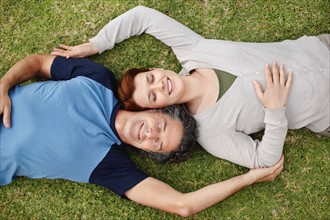 Happy couple relaxing on the grass together. Photo. momentimages