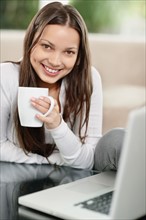 Woman drinking coffee while browsing the internet. Photo : momentimages