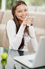 Woman drinking water while browsing the internet. Photo. momentimages