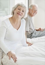 Relaxed senior couple sitting on bed. Photo : momentimages
