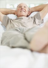 Relaxed senior man lying on bed. Photo. momentimages