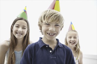 Three children wearing birthday hats. Photo. momentimages