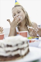 Young girl eating birthday cake. Photo : momentimages