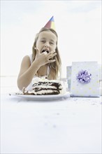 Young girl eating birthday cake. Photo. momentimages