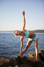 Athletic woman stretching by the ocean. Photo. Take A Pix Media