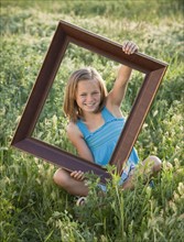 Young girl holding picture frame. Photo : Mike Kemp