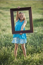 Young girl holding picture frame. Photo : Mike Kemp